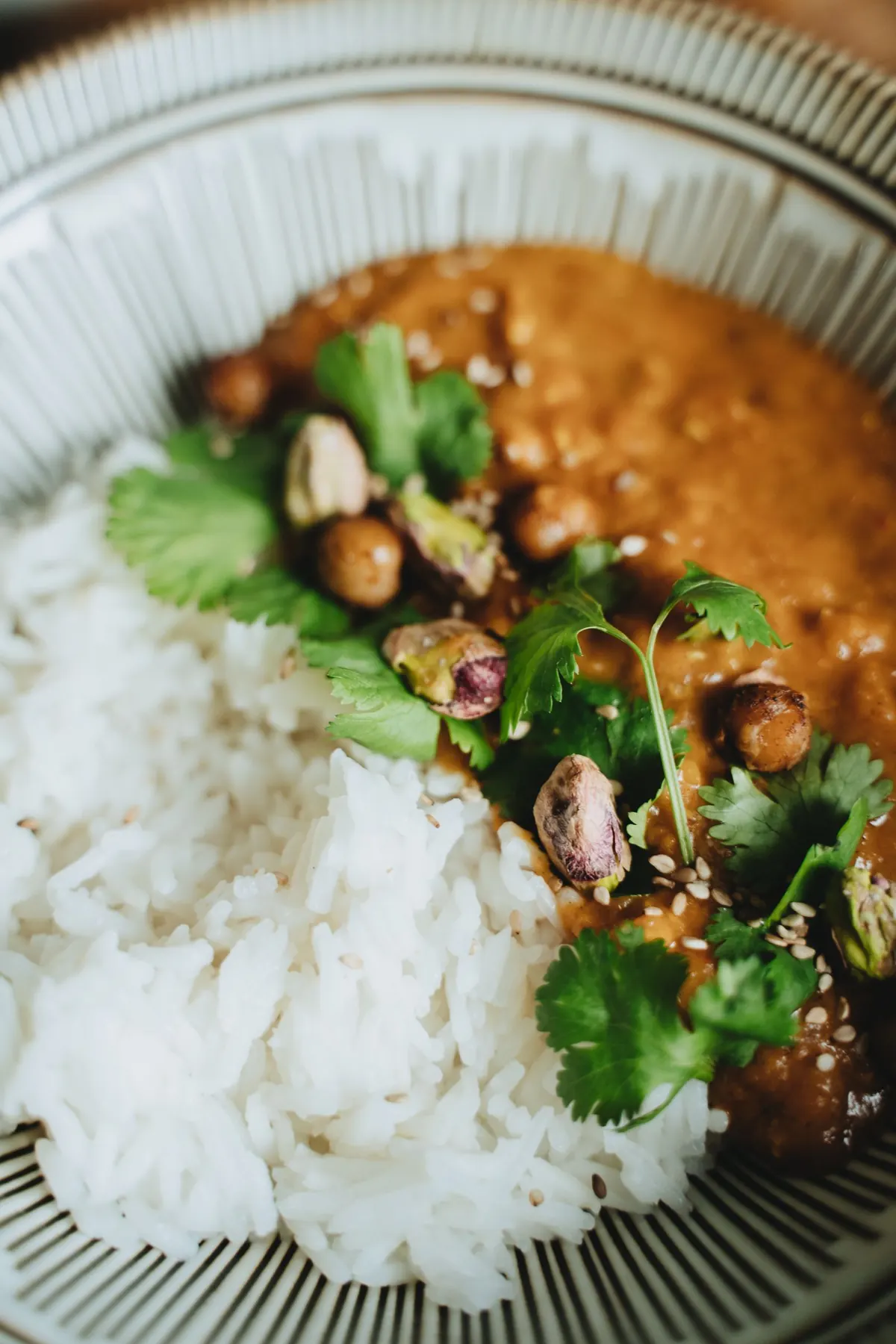 A small bowl of chickpea curry with fresh coriander, served beside rice