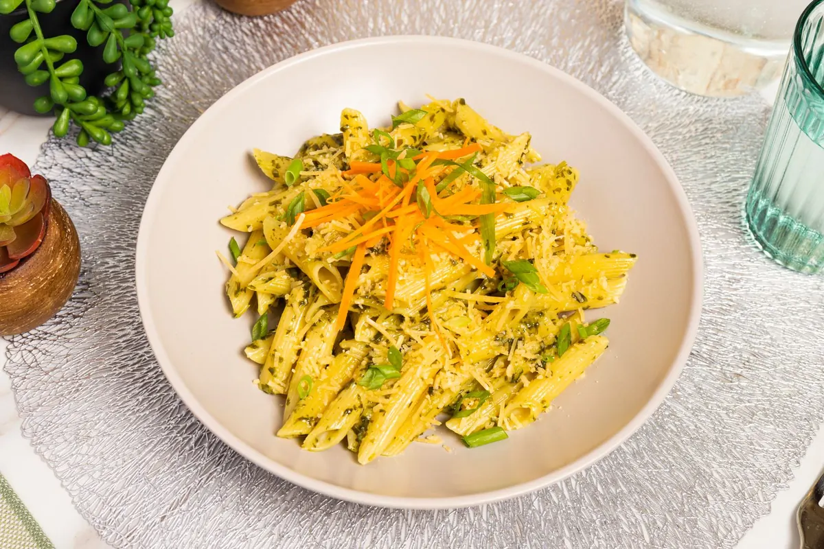 A plate of penne pasta tossed in green pesto