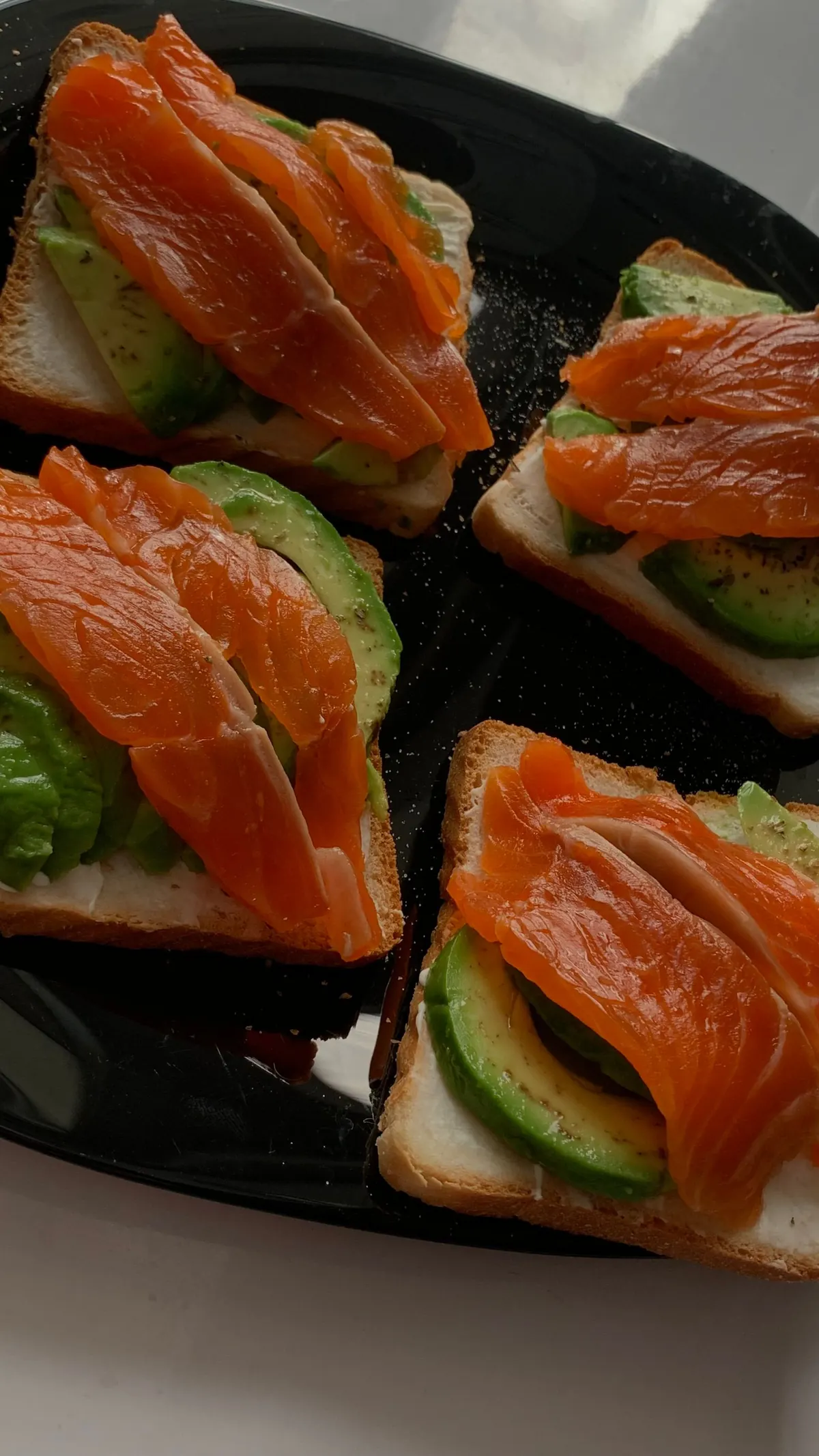 Smoked salmon on avocado toast on a dark slate board