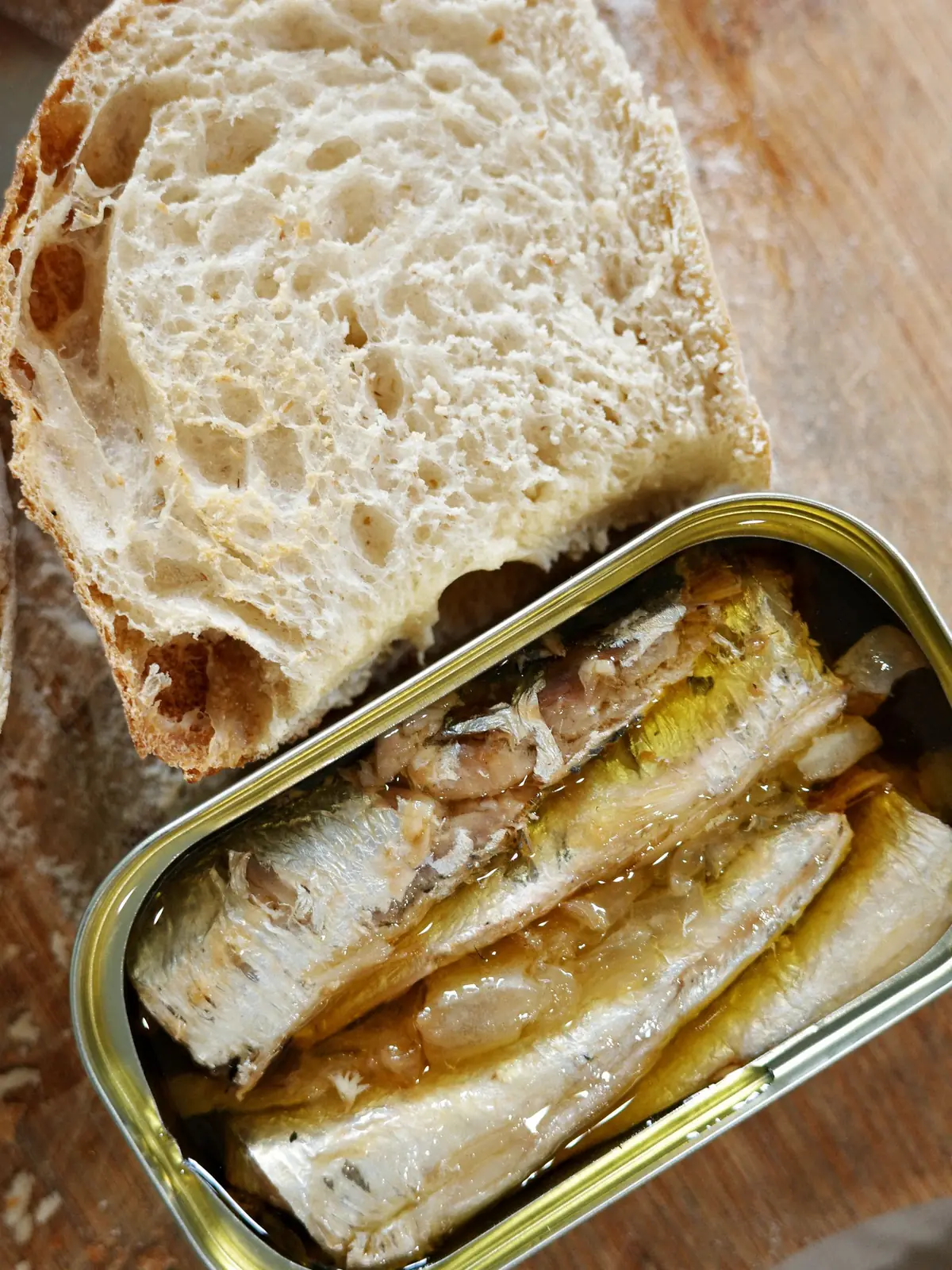 An open tin of sardines beside slices of crusty bread